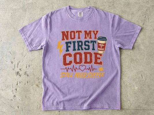 "Not My First Code, Still Need Coffee" bold retro Comfort Colors tee. Funny ER/ICU nurse gift shirt.